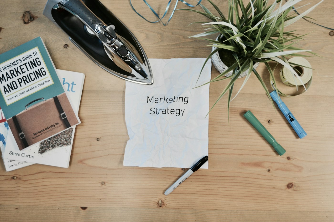 A marketing strategy note, books and pens on a wooden desk